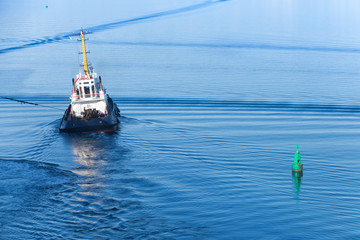 Small tug boat goes on a fairway