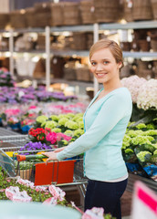 happy woman with shopping trollye buying flowers