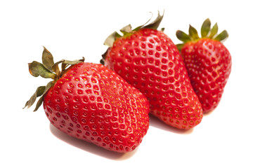 Three ripe strawberries with leaves on white background