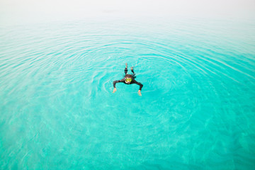 Man in diving suit swims in sea, top view. Activities on water. Diver