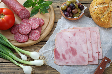 salame e prosciutto cotto con verdure e pane su tavolo di legno rustico