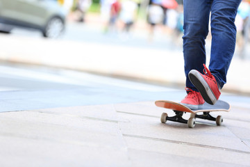 young skateboarder legs riding on skateboard on city