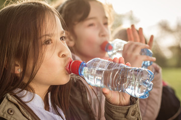Photo of two girls drinking water from PET bottle