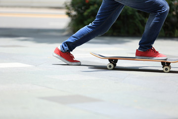 Fototapeta na wymiar young skateboarder legs riding on skateboard on city