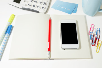 Work table with blank notebook and phone