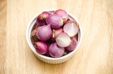Close up of fresh shallots in the bowl on wooden background