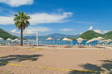 beach volleyball court with sunshades and sunbeds at background