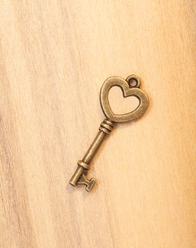 Vintage key with heart shape ring hole on wooden background