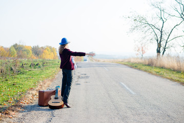 Young lonely woman and baby hitchhiking on rural roadside