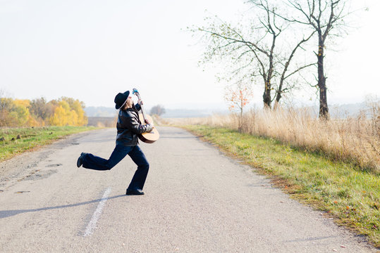 Picture of excited giutarist playing guitar crazy crossing road
