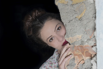 Brunette girl hidden behind a wall
