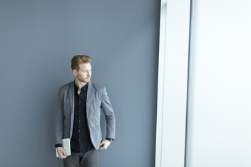 Young man with tablet by the wall