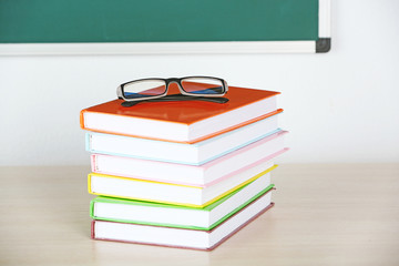 Heap of books and glasses on table in class