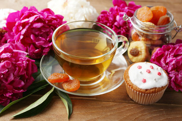 Composition with cup of herbal tea and peony flowers on wooden background