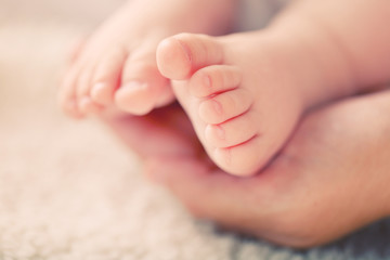 Obraz na płótnie Canvas Adult hands holding baby feet, closeup