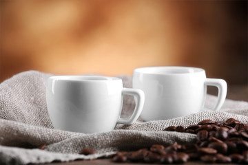 Cups of coffee and beans on blurred background