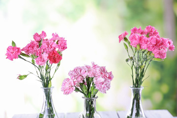 Naklejka na ściany i meble Beautiful bouquet of pink carnation in vases on bright background