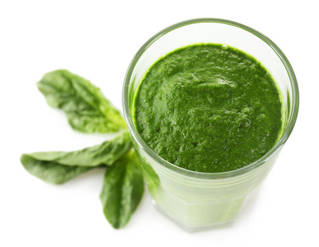 Glass of green vegetable juice with basil isolated on white