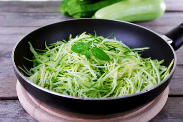 Grated zucchini and squash in pan on wooden table close up