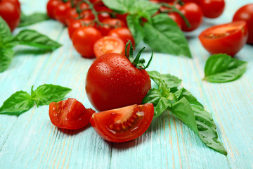 Fresh tomatoes with basil on wooden table close up