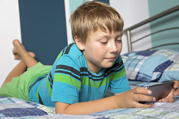 Teenage Boy Lying On Bed Texting A Message