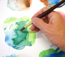 artist hand holding brush working on colorful artwork