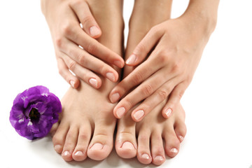 Female feet at spa pedicure procedure with flower isolated on white