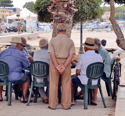 gruppo di anziani che giocano a carte seduti ad un tavolo all'aperto sotto un albero - 88633886