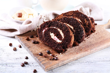 Delicious chocolate roll on wooden cutting board, closeup