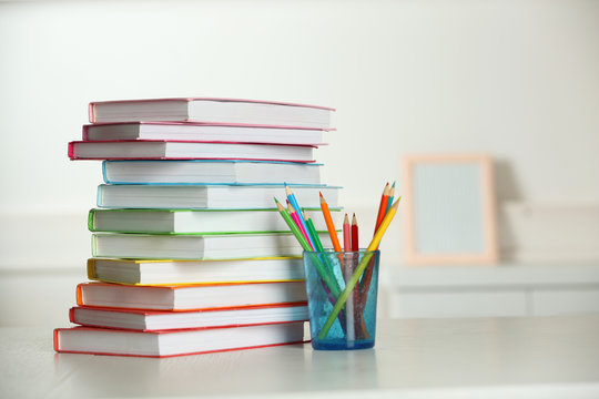 Colorful books and pencil on table in room