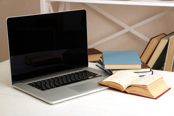 Laptop with books on table in room
