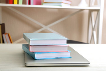 Stack of books with laptop on table close up
