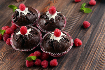 Delicious chocolate cupcakes with berries and fresh mint on wooden table close up