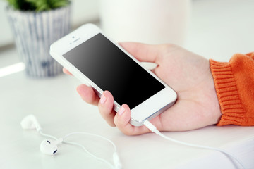 Music smartphone in female hand, on light background