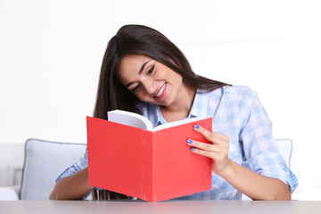 Naklejka premium Young girl reading book in room