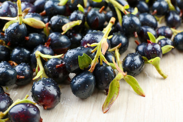 Pile of wet black currants on wooden table, closeup