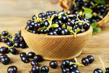 Fresh black currants in bowl on wooden table, closeup