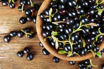 Fresh black currants in bowl on wooden table, top view