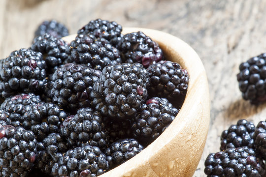 Fresh blackberries in a wooden bowl, selective focus