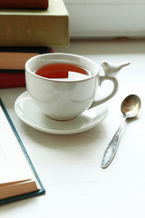 Cup of tea with stack of books on windowsill, closeup