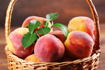 Fresh peaches in wicker basket on wooden table, closeup