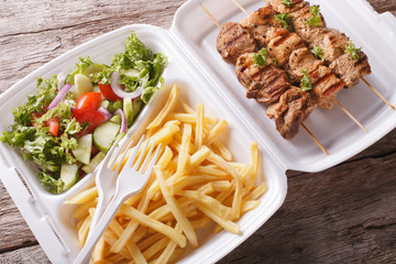 Lunch Box: kebabs, fries and fresh salad in tray close-up. Horizontal
