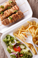 Street food: kebabs, fries and salad in tray close-up. vertical top view 
