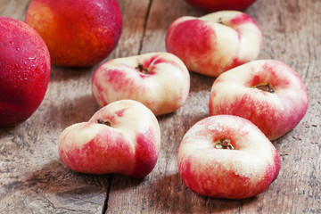Flat pink nectarine on an old wooden background, selective focus
