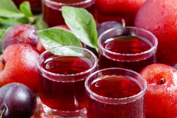 Delicious fresh juice of red and blue sweet plums in a glass on