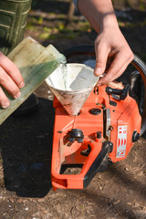 Hand refilling the chainsaw with fuel