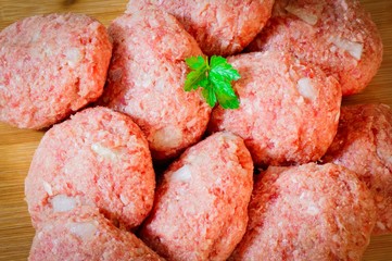 Mehrere rohe Frikadellen vor dem Braten auf Holztisch