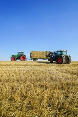 Traktor beim Verladen von Strohballen  auf einen Anhänger