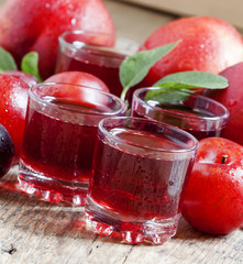 Delicious fresh juice of red and blue sweet plums in a glass on