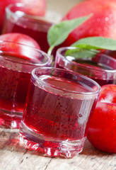 Delicious fresh juice of red and blue sweet plums in a glass on